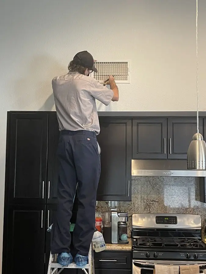 Technician inspecting an air vent during HVAC service in San Elizario